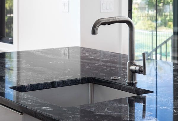 Black marble countertops around a stainless steel faucet